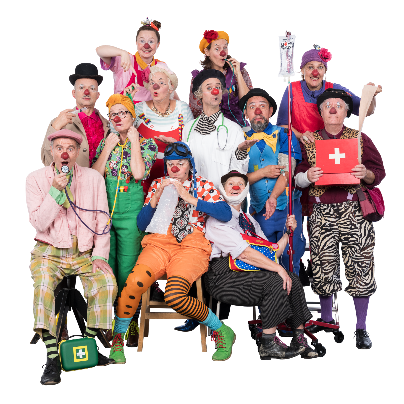 Foto på tolv sjukhusclowner som står tätt tillsammans. De håller i olika sjukhusprylar såsom spruta, kräkpåse och förbandslåda.